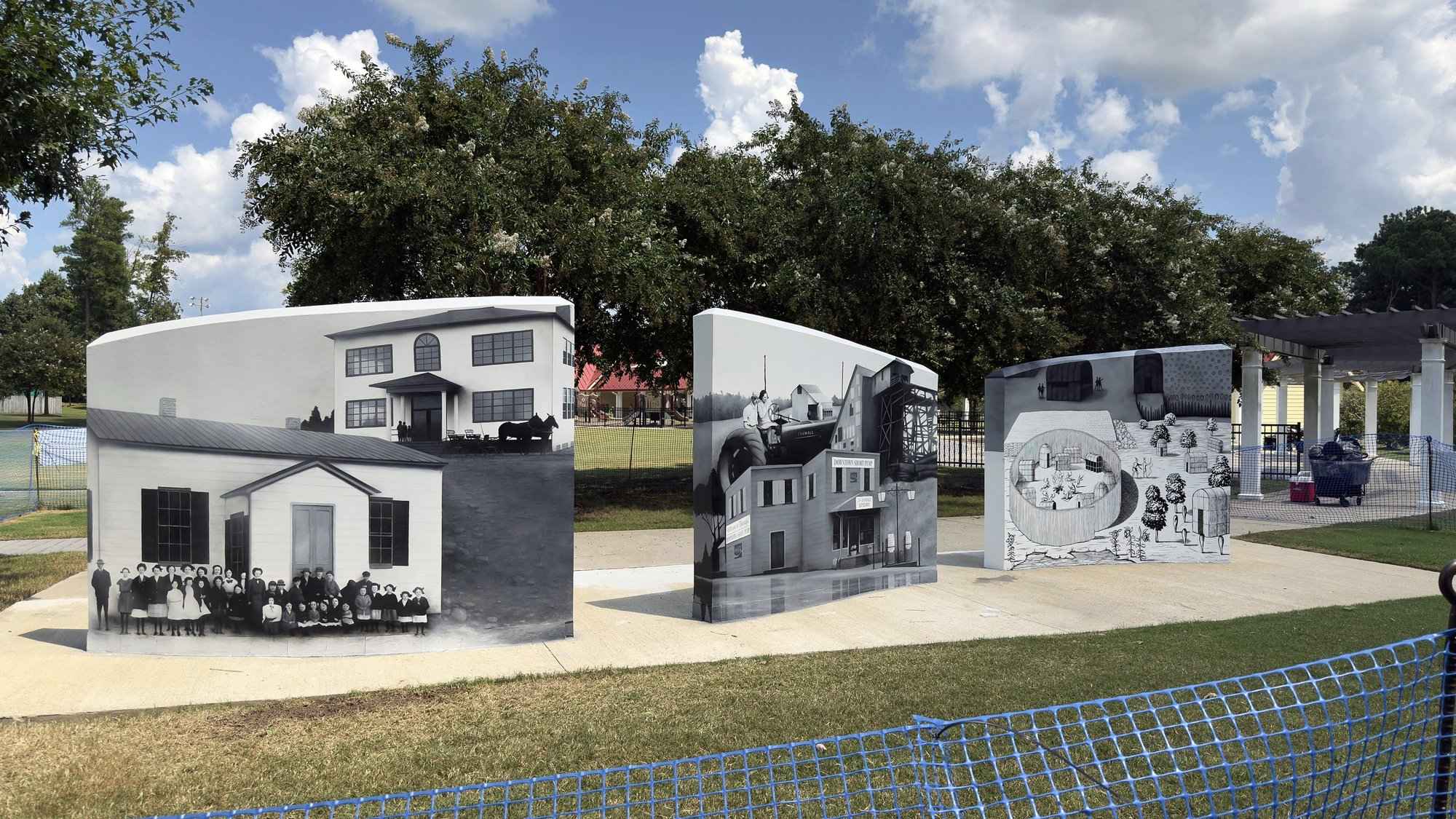 The first wall painted, a house and buildings in grayscale, the other two walls still white
