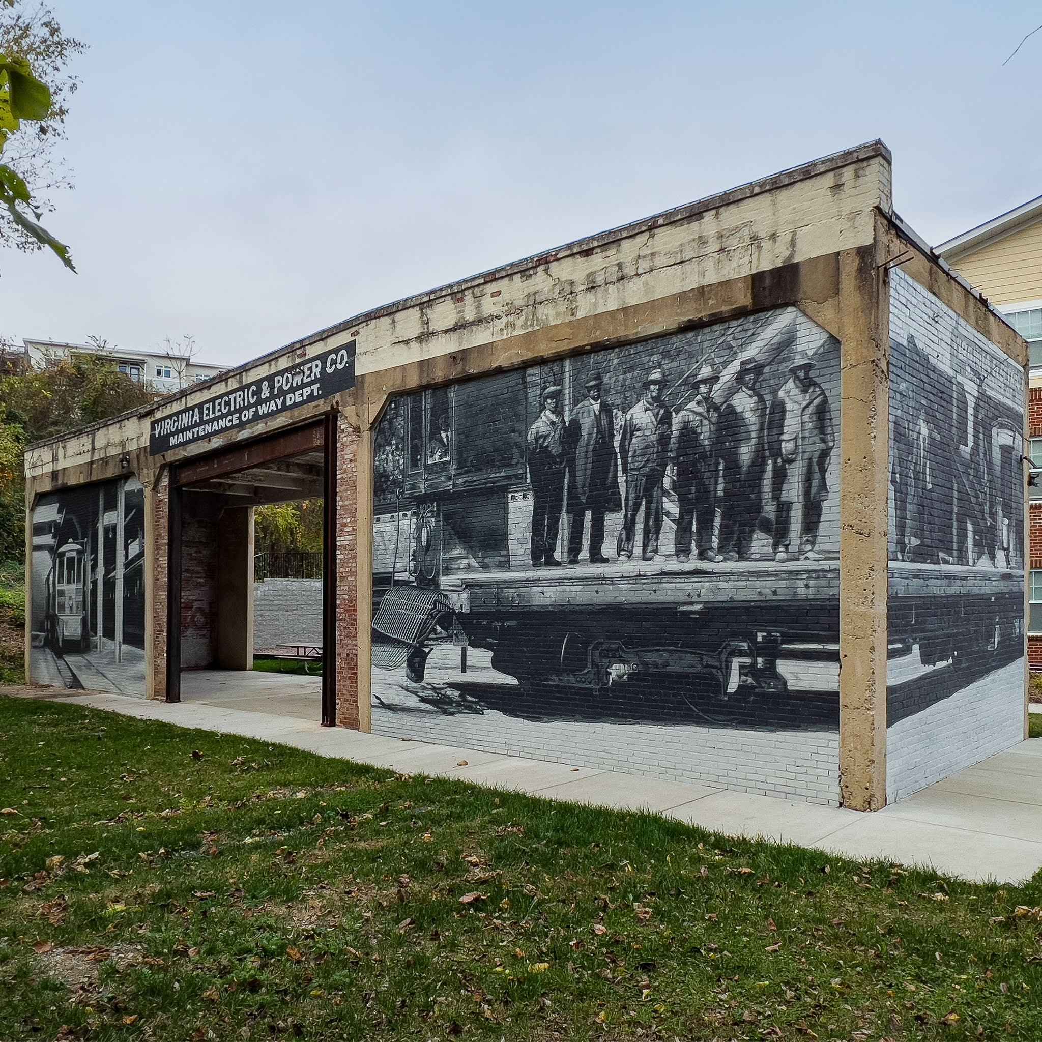 The finished barn from the front corner: the restored sign over the open bay, the streetcar on the left wall and the crew on the long wall