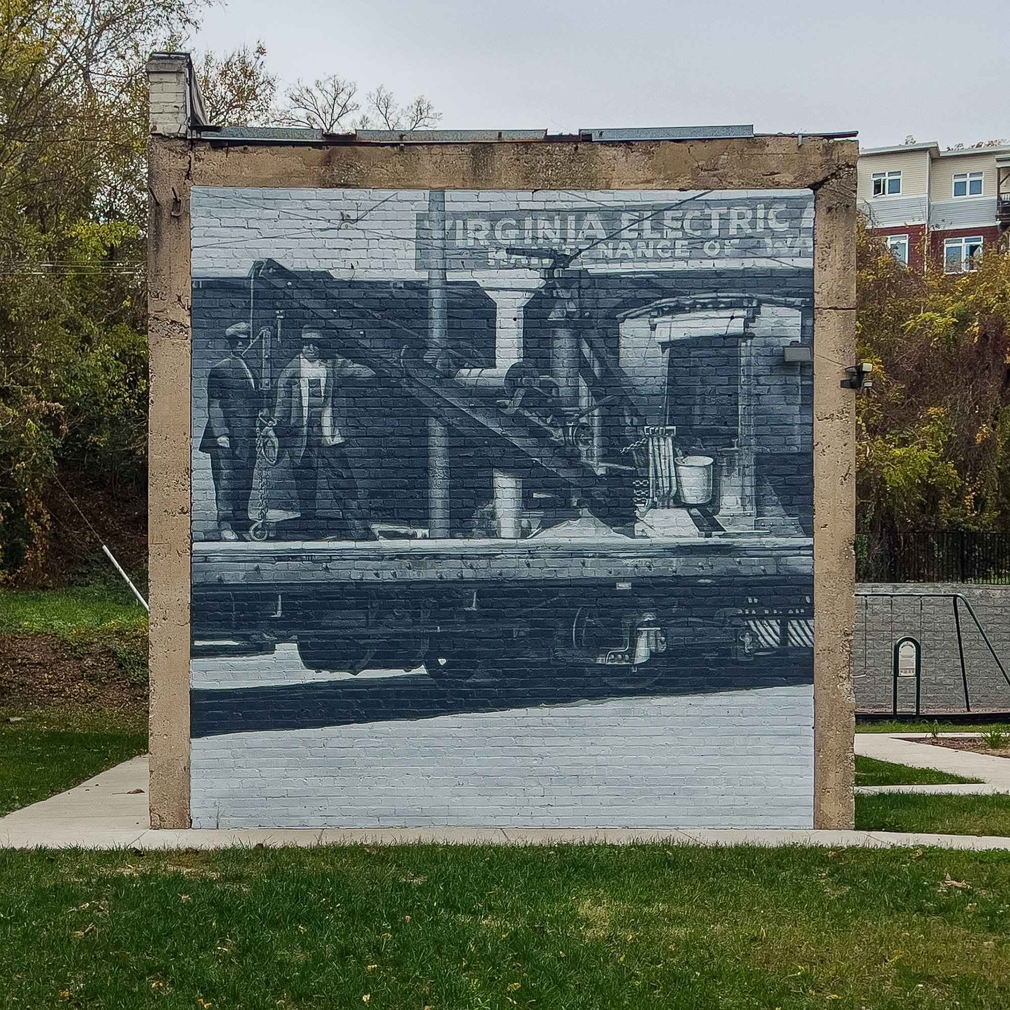 The end wall square on: two workers and the crane car, with the 1925 sign visible behind them inside the painted photograph