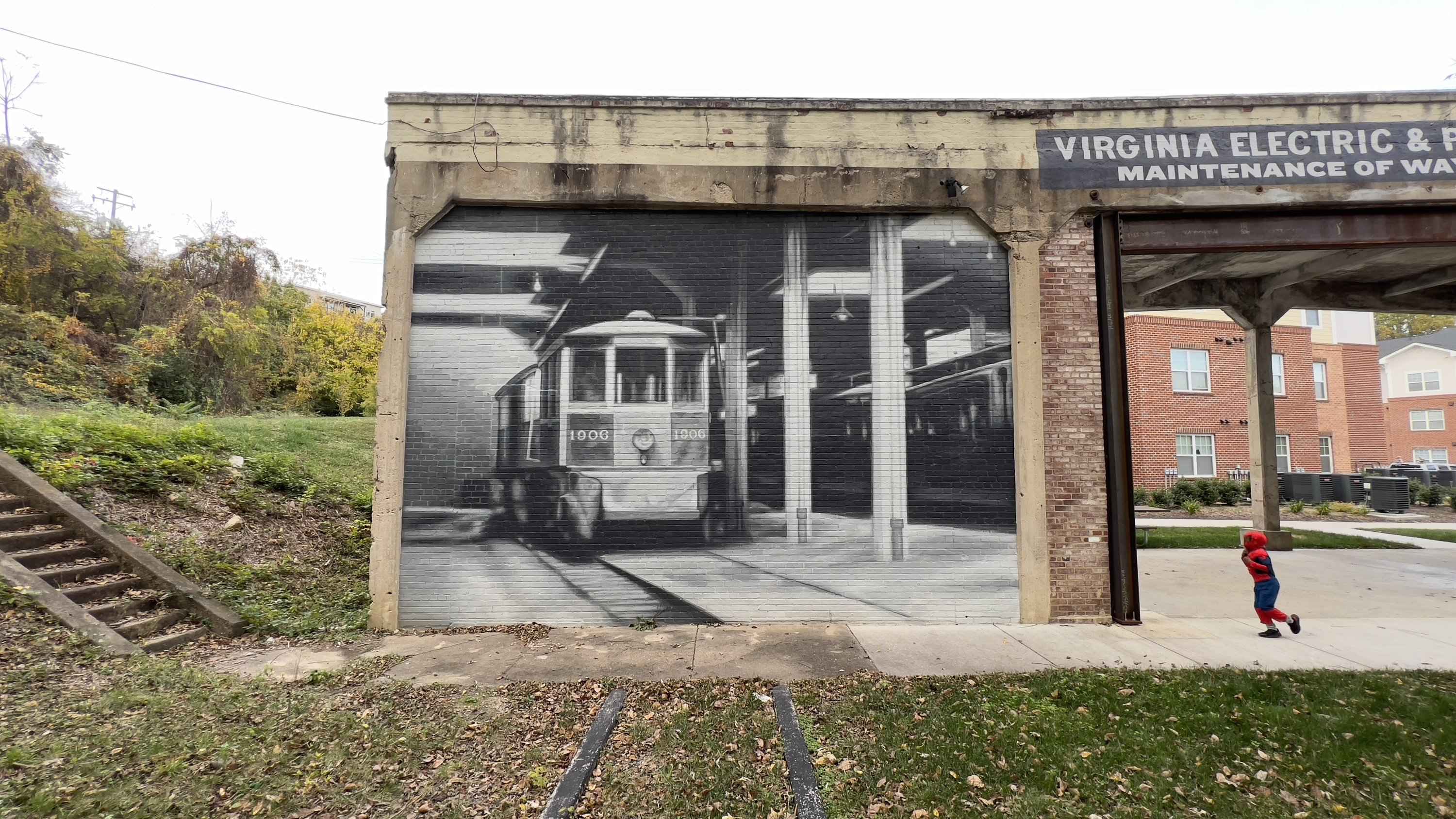 A child running past the painted streetcar bay on the sidewalk, the restored sign overhead